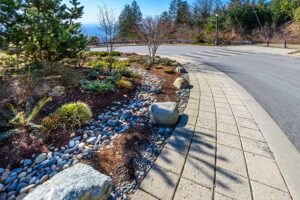 beautifully designed hardscape walkway in gray pavers, larger rocks and other elements in a garden surrounding a commercial property entrance